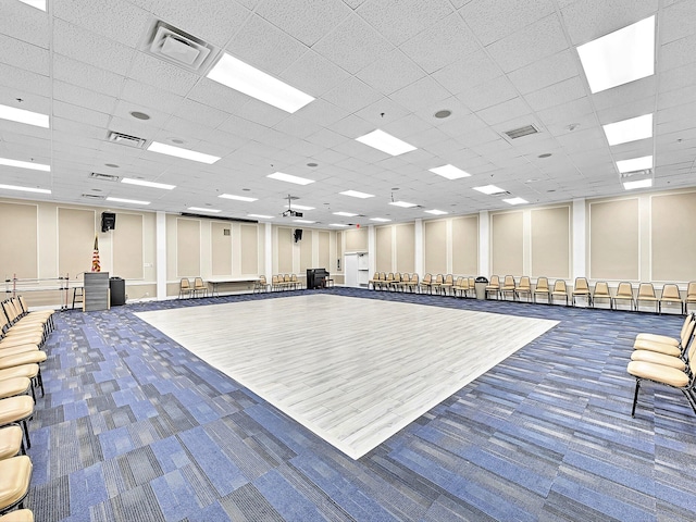 interior space featuring ceiling fan, dark carpet, and a paneled ceiling