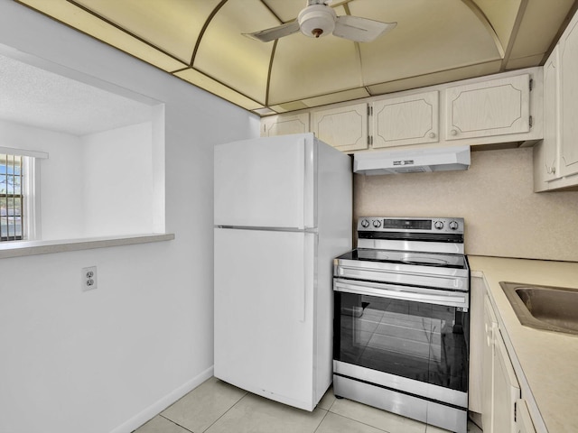 kitchen featuring white refrigerator, ceiling fan, light tile flooring, and stainless steel range with electric cooktop