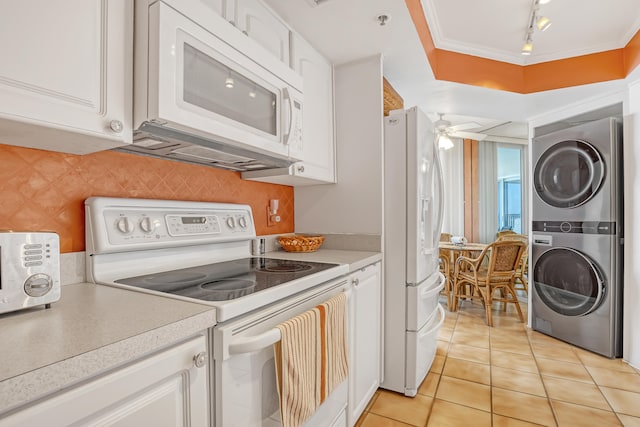 kitchen with white appliances, white cabinetry, stacked washer and clothes dryer, ornamental molding, and ceiling fan