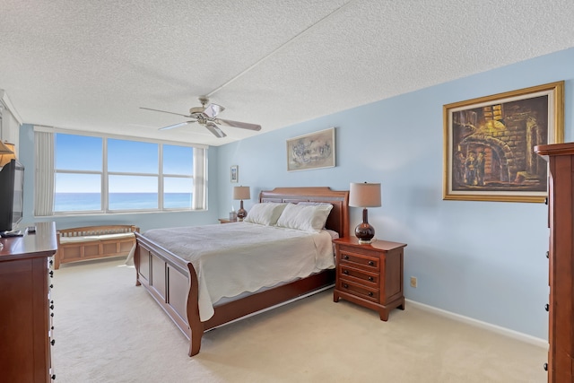 carpeted bedroom with ceiling fan and a textured ceiling