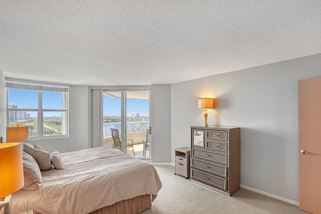 bedroom with light colored carpet, a water view, access to outside, and a textured ceiling