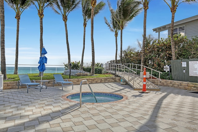 exterior space featuring a water view, a hot tub, and a patio