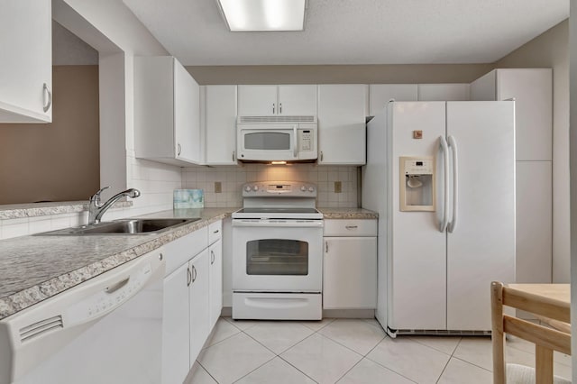 kitchen with decorative backsplash, white appliances, sink, white cabinets, and light tile patterned flooring