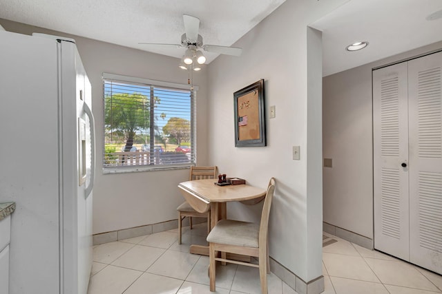 tiled dining area with a textured ceiling and ceiling fan