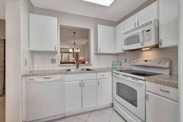 kitchen featuring white appliances, sink, hanging light fixtures, light tile patterned flooring, and white cabinetry