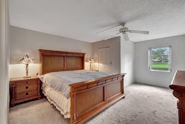 carpeted bedroom featuring ceiling fan, a closet, and a textured ceiling