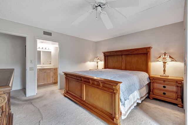 carpeted bedroom with a textured ceiling, connected bathroom, and ceiling fan