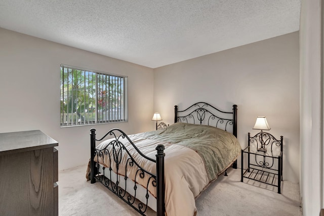 bedroom featuring light carpet and a textured ceiling