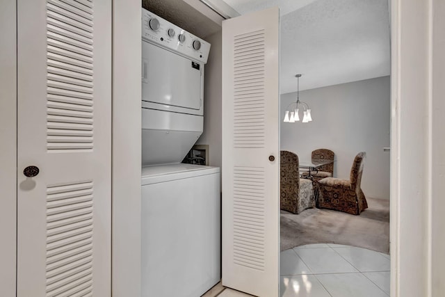 laundry area featuring light colored carpet, stacked washer / dryer, and an inviting chandelier