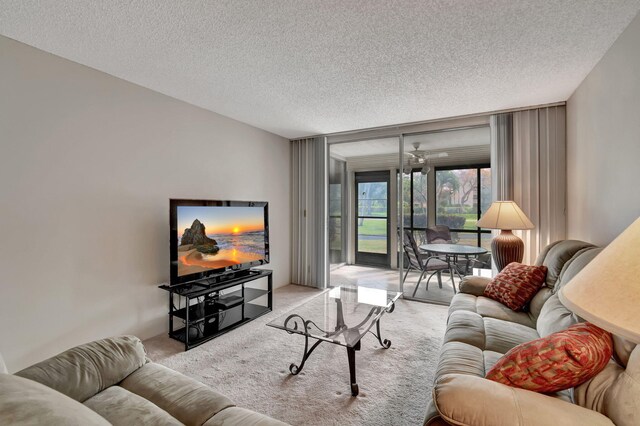 carpeted living room featuring a textured ceiling, a wall of windows, and ceiling fan