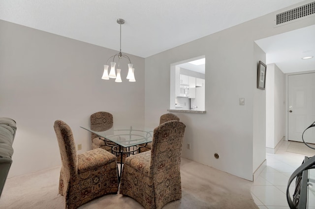 dining space featuring light carpet and a chandelier