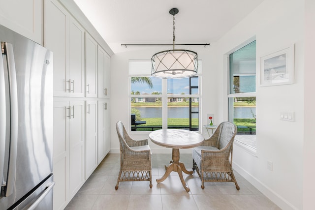 dining space featuring a water view and light tile floors