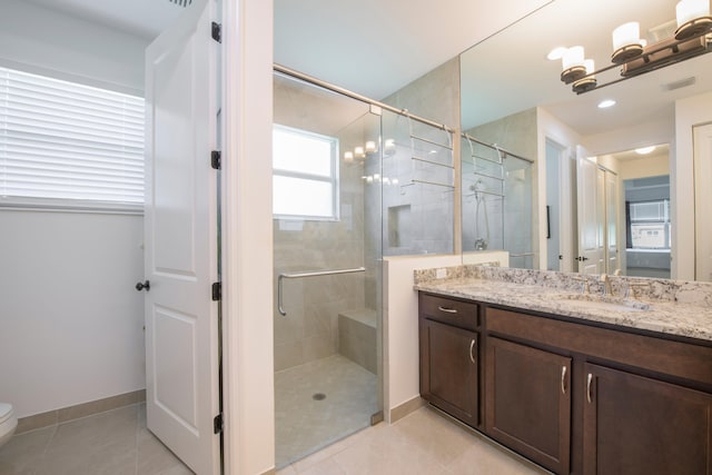 bathroom with a shower with door, vanity, tile floors, and toilet