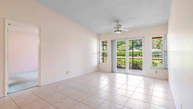 empty room with a textured ceiling, ceiling fan, and light tile flooring