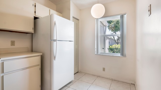 kitchen with decorative light fixtures, light tile floors, white fridge, and white cabinets