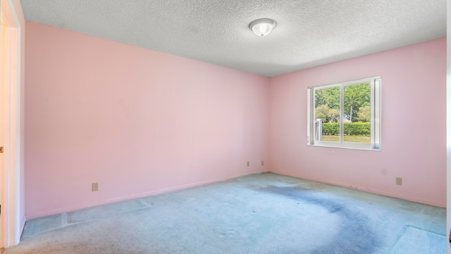 carpeted empty room featuring a textured ceiling