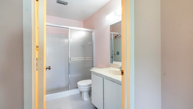 bathroom with vanity with extensive cabinet space, a shower with shower door, toilet, and tile flooring