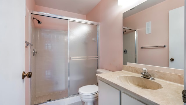 bathroom featuring vanity with extensive cabinet space, a shower with shower door, and toilet