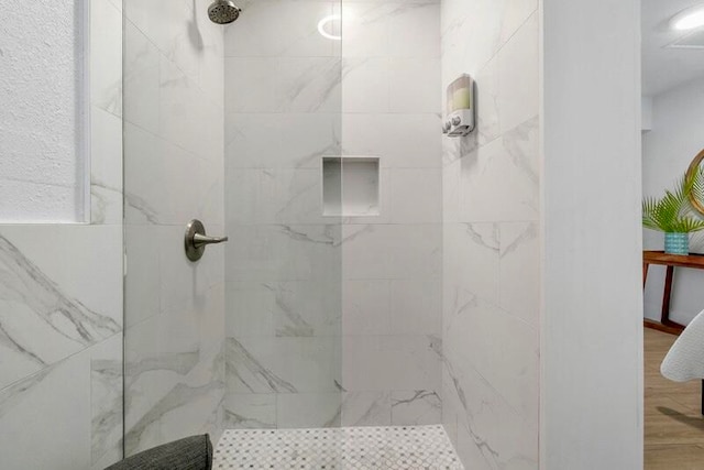 bathroom with hardwood / wood-style flooring and a tile shower