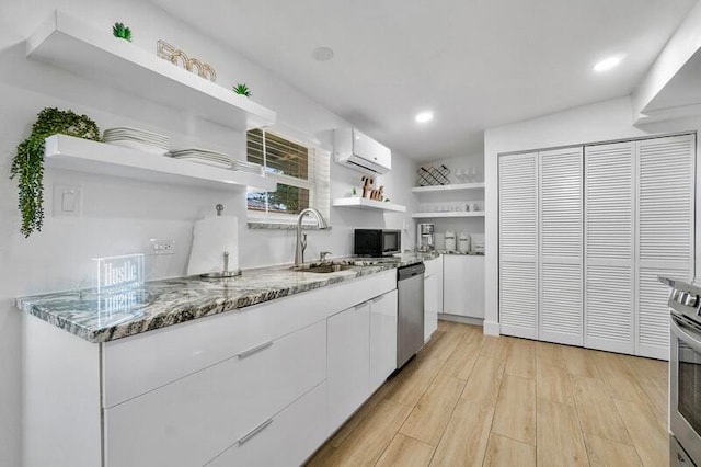 kitchen with stone countertops, light hardwood / wood-style floors, dishwasher, white cabinets, and a wall mounted AC