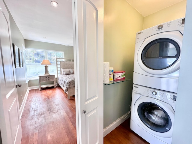 washroom with stacked washing maching and dryer and wood-type flooring