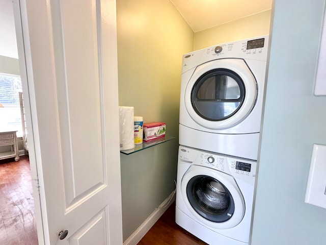 laundry area featuring dark wood-type flooring and stacked washer and clothes dryer