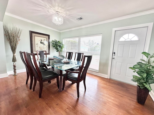 dining area featuring crown molding, an inviting chandelier, and wood-type flooring