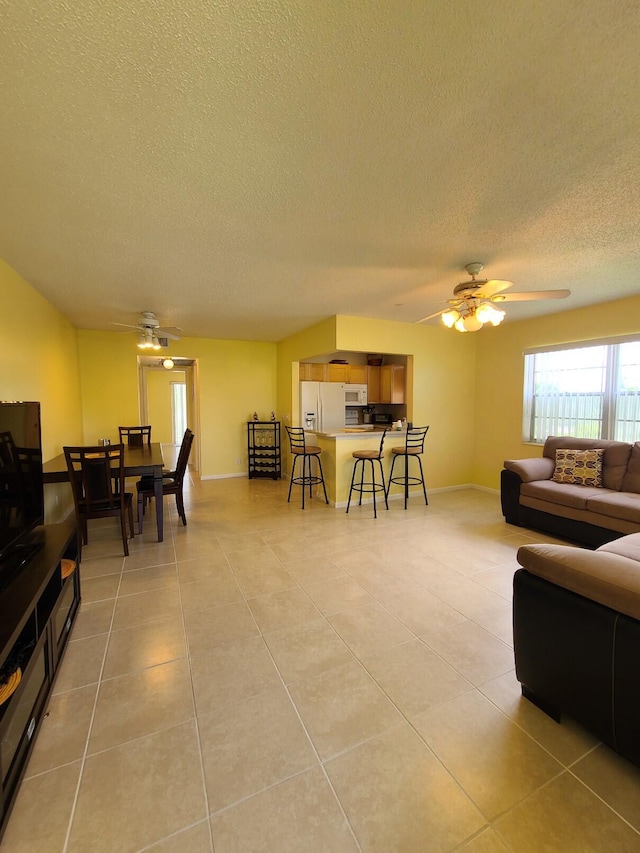 tiled living room with a textured ceiling and ceiling fan