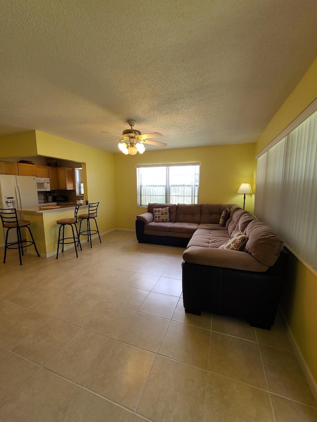 living room with a textured ceiling, ceiling fan, and light tile patterned floors