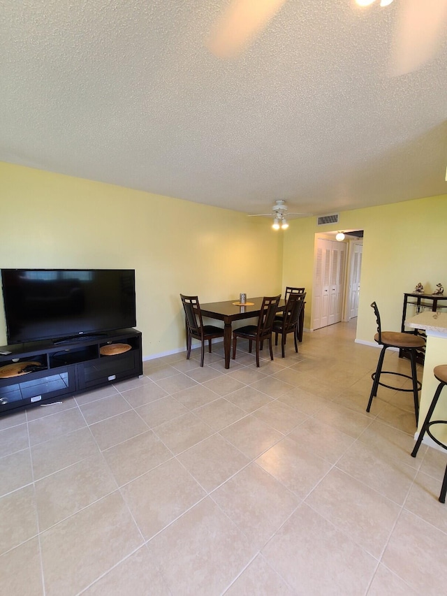 dining area featuring light tile patterned flooring, ceiling fan, and a textured ceiling