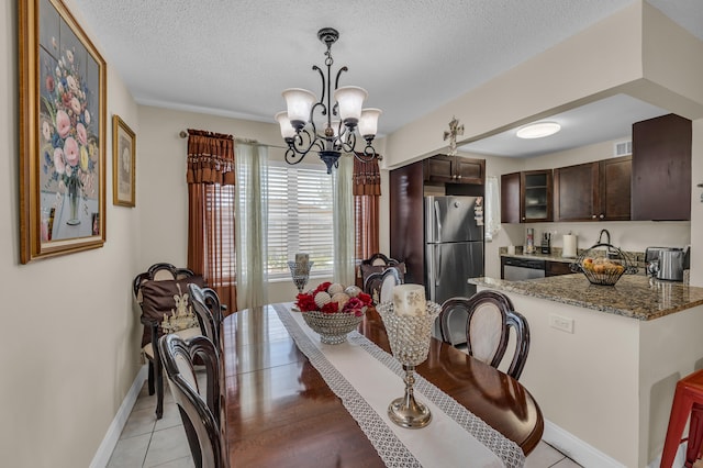 dining space featuring a textured ceiling, a notable chandelier, and light tile floors