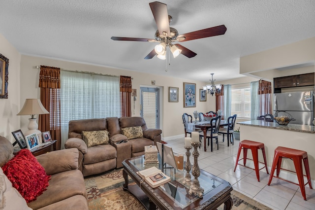 living room featuring ceiling fan with notable chandelier, light tile floors, and a textured ceiling