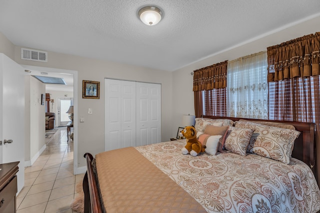 tiled bedroom with a closet and a textured ceiling