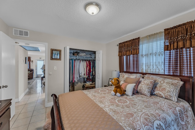 bedroom featuring a closet, light tile floors, and a textured ceiling