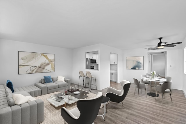 living room featuring light hardwood / wood-style flooring and ceiling fan