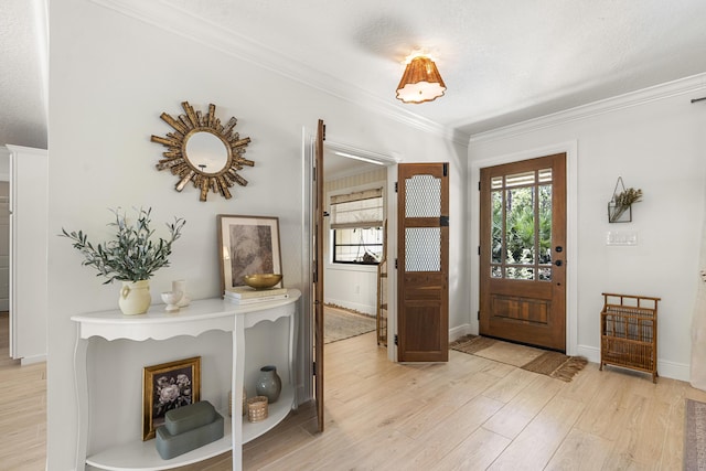 foyer with light hardwood / wood-style floors, ornamental molding, and a textured ceiling