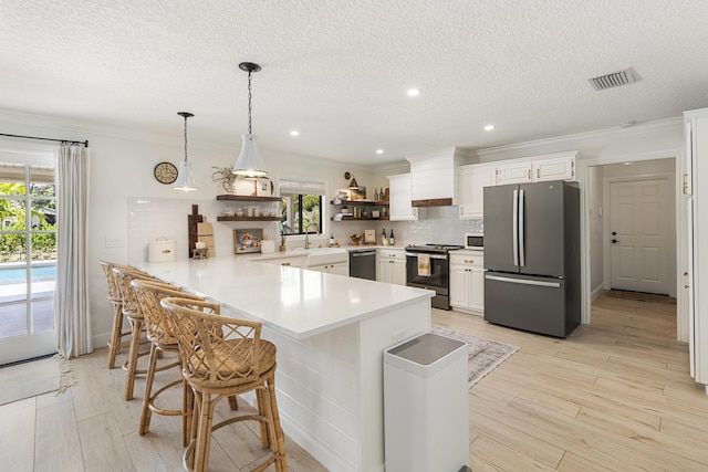 kitchen featuring white cabinetry, kitchen peninsula, a breakfast bar area, stainless steel appliances, and backsplash