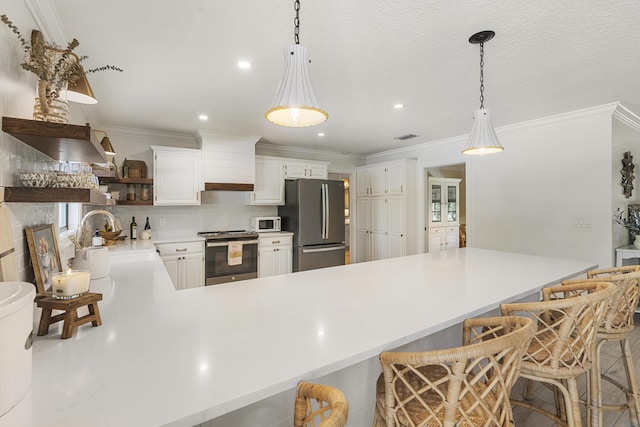 kitchen with pendant lighting, a breakfast bar, sink, white cabinetry, and appliances with stainless steel finishes