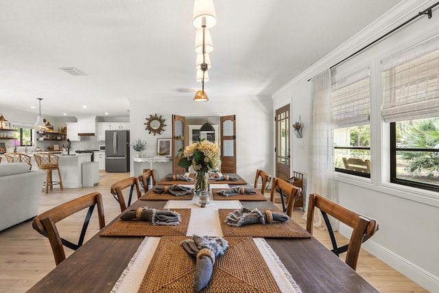 dining area with crown molding, light hardwood / wood-style floors, and sink