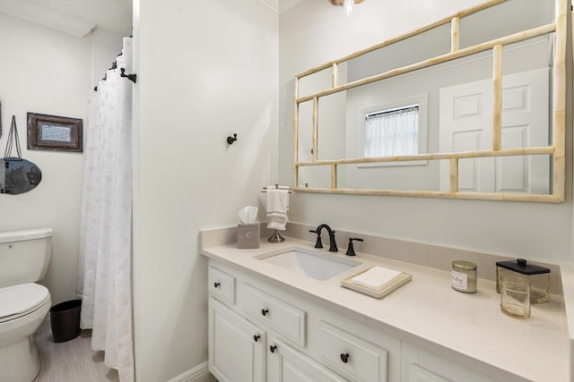 bathroom with toilet, vanity, and ornamental molding