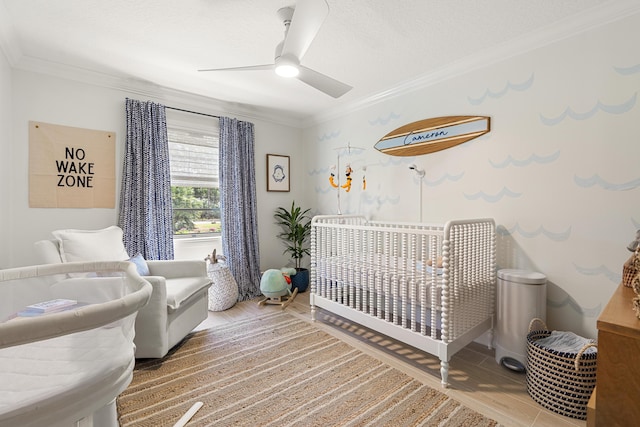 bedroom featuring hardwood / wood-style flooring, ceiling fan, ornamental molding, and a nursery area