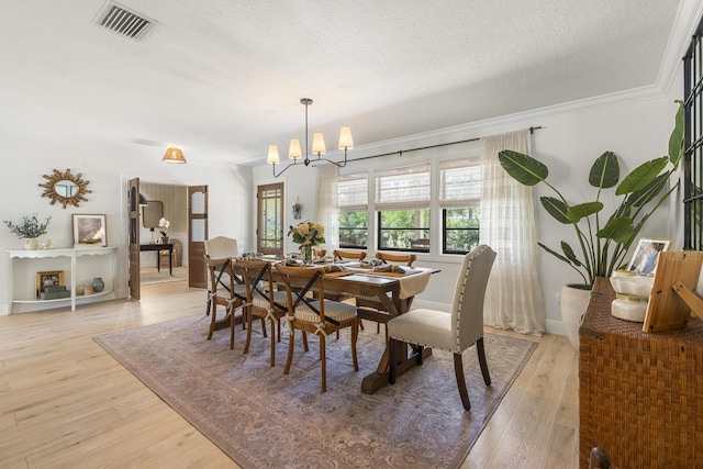 dining room with a textured ceiling, a chandelier, crown molding, and light hardwood / wood-style floors