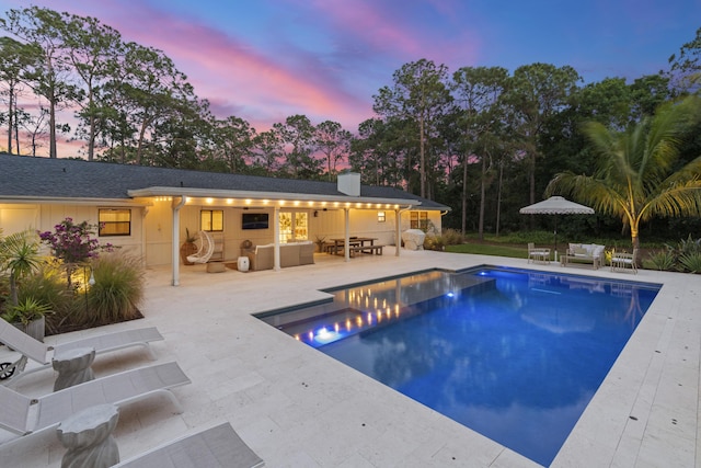 pool at dusk with an outdoor living space and a patio area