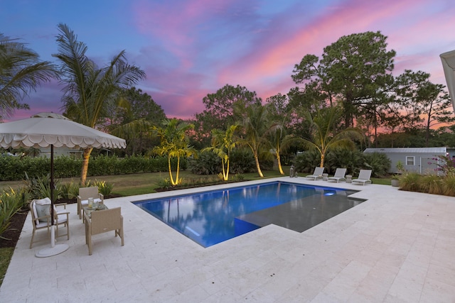 pool at dusk with a patio area