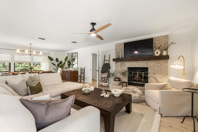 living room featuring a brick fireplace, ceiling fan with notable chandelier, ornamental molding, and light hardwood / wood-style floors