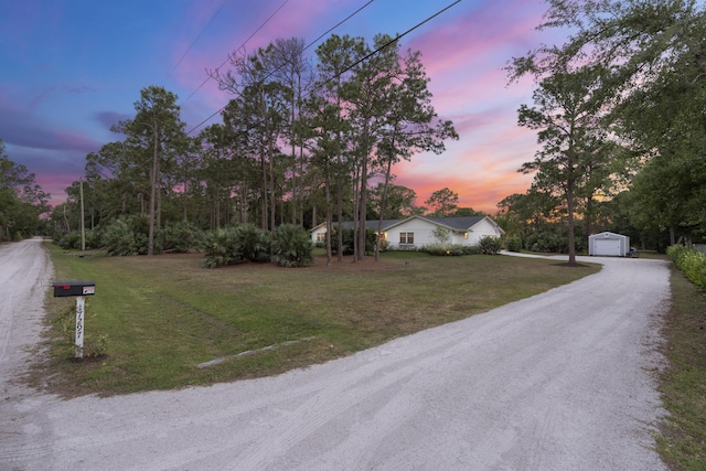 view of front of property featuring a garage, an outbuilding, and a lawn