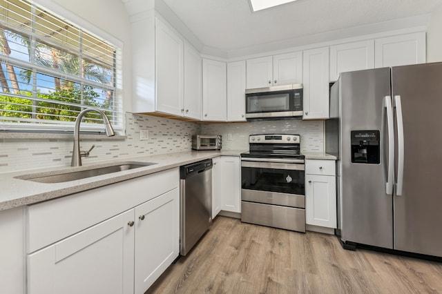 kitchen with appliances with stainless steel finishes, light hardwood / wood-style flooring, sink, and white cabinets