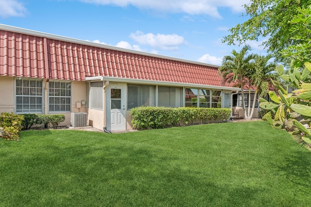 rear view of property featuring a yard and central air condition unit