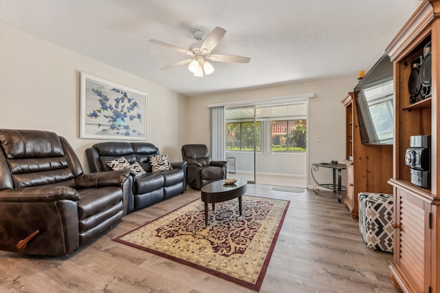 living room featuring wood-type flooring, ceiling fan, and a textured ceiling