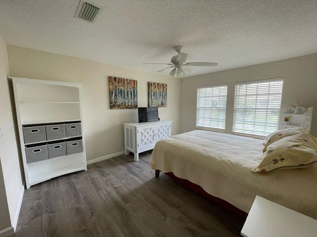 bedroom featuring ceiling fan, dark hardwood / wood-style floors, and a textured ceiling